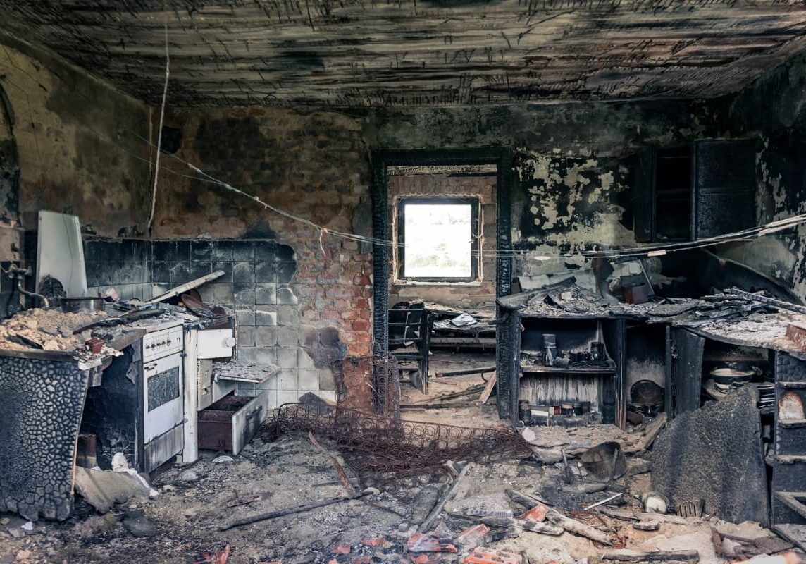 Kitchen-After-Fire-Damage Kitchen With A Damaged Stove, Oven, And Appliances, Showing Signs Of Fire Damage And Charred Surfaces.